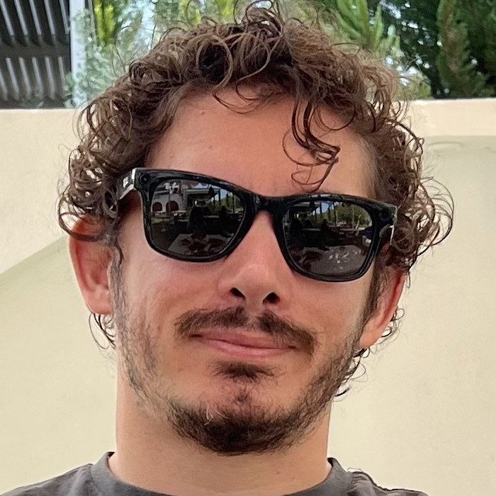 The selfie — jaw, half-smile, mustache line, ringlets over the forehead.
